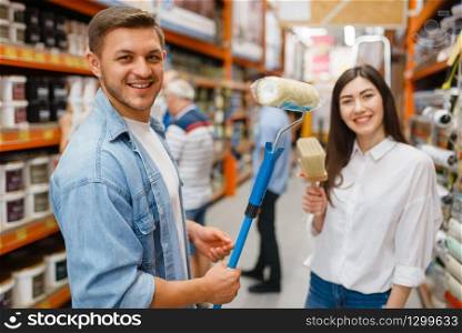 Young couple buying repair tools in hardware store. Male and female customers look at the goods in diy shop