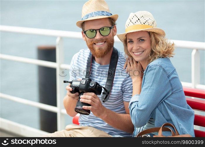 young couple by the sea holding a camera
