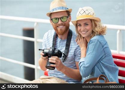 young couple by the sea holding a camera