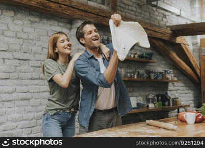 Young couple caking pizza in rustic kitchen together