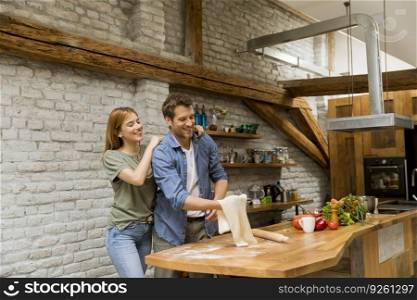 Young couple caking pizza in rustic kitchen together