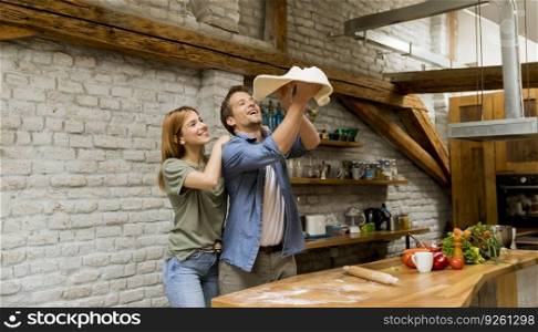 Young couple caking pizza in rustic kitchen together