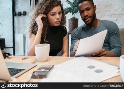 Young couple calculating and paying bills on a laptop from home. Couple planning monthly budget.