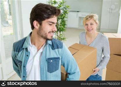 young couple carrying box in apartment