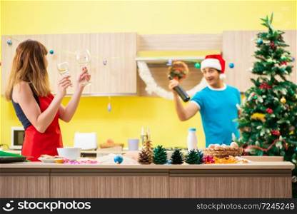Young couple celebrating Christmas in kitchen . The young couple celebrating christmas in kitchen 
