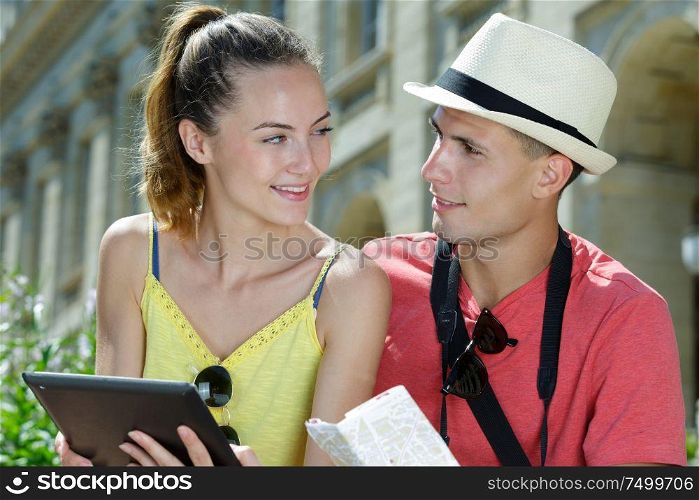young couple checking digital and printed map
