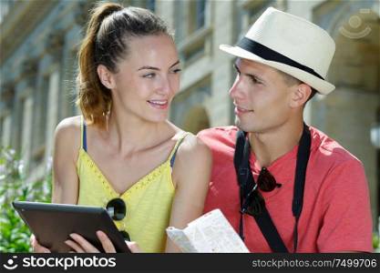 young couple checking digital and printed map