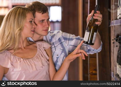 Young couple chooses the wine at supermarket