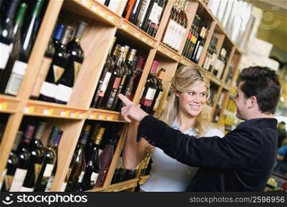 Young couple choosing a wine bottle in a supermarket