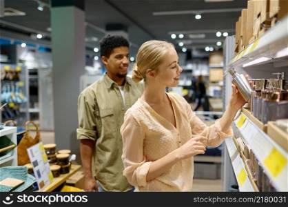 Young couple choosing bottle for soap or wash gel home accessories in household goods store. Couple choosing home accessories in store