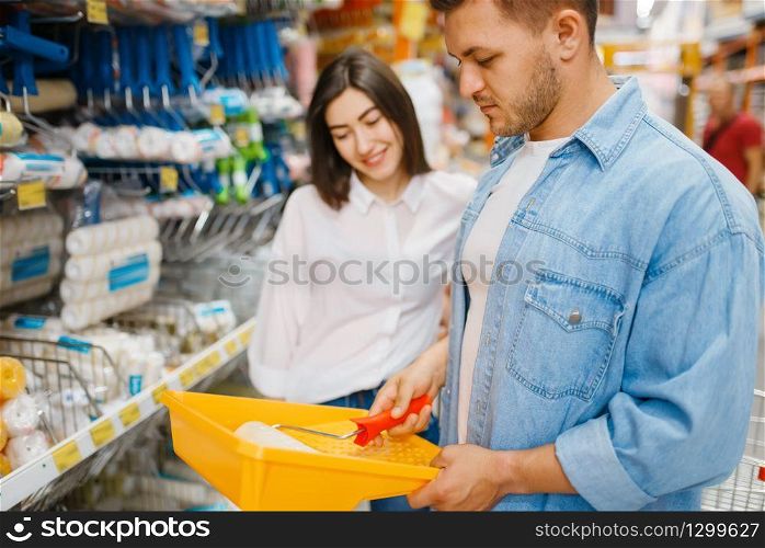 Young couple choosing the platen for painting in hardware store. Male and female customers look at the goods in diy shop