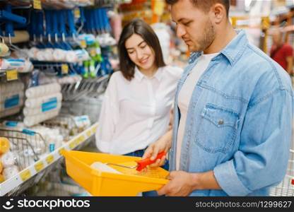 Young couple choosing the platen for painting in hardware store. Male and female customers look at the goods in diy shop