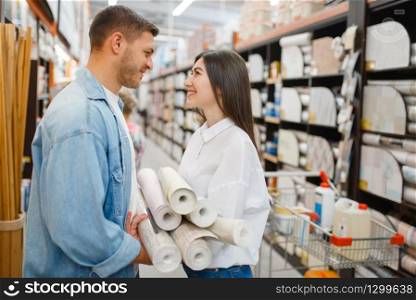 Young couple choosing wallcovering in hardware store. Male and female customers look at the goods in diy shop