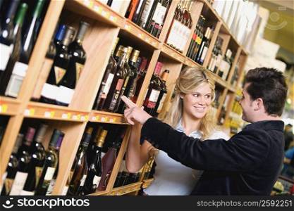 Young couple choosing wine in a liquor store