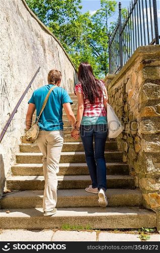Young couple climbing up city stairs holding hands leisure time