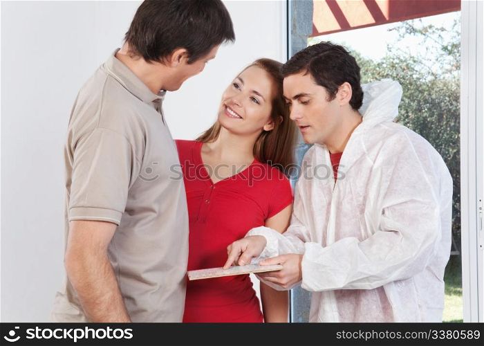 Young couple consulting the painter for the color