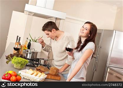 Young couple cooking in kitchen together drinking red wine