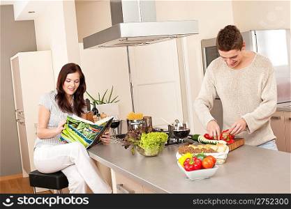 Young couple cooking in kitchen together with cookbook