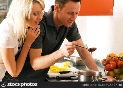 Young couple cooking (in this case: strawberry sauce for dessert)