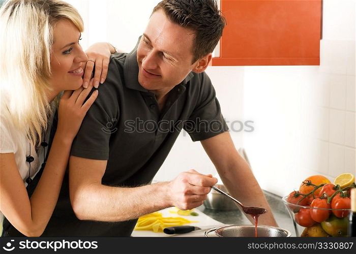 Young couple cooking (in this case: strawberry sauce for dessert)