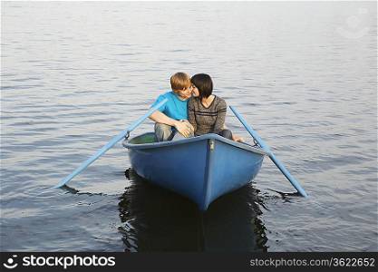Young Couple Cuddling in Rowboat on Lake
