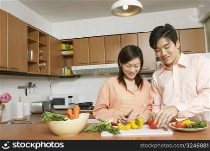 Young couple cutting vegetables at a kitchen counter