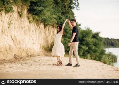 Young couple dancing at beach on sunny day Happy Romantic young Couple Enjoying Beautiful Sunset Walk on the Beach. Young couple dancing at beach on sunny day Happy Romantic young Couple Enjoying Beautiful Sunset Walk on the Beach.