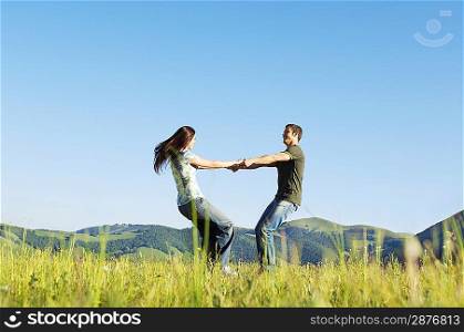 Young couple dancing in mountain field, side view, ground view