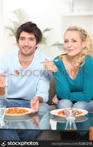 Young couple dining in front of TV