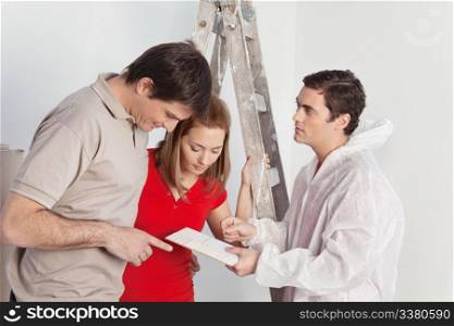 Young couple discussing color options with house painter