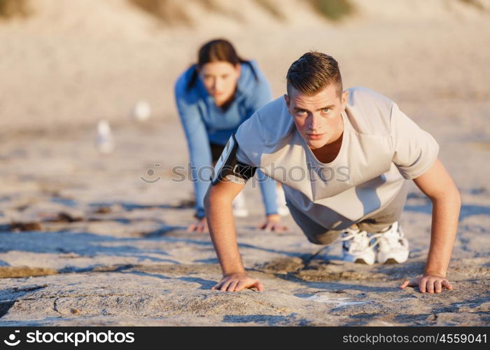 Young couple doing push ups on ocean beach. Young couple of man and woman doing push ups on ocean beach