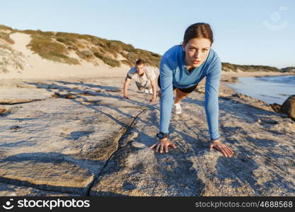 Young couple doing push ups on ocean beach. Young couple of man and woman doing push ups on ocean beach