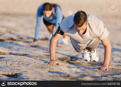 Young couple doing push ups on ocean beach. Young couple of man and woman doing push ups on ocean beach