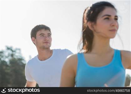 Young couple doing stretching yoga exercises with sea on the background