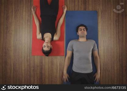 Young couple doing yoga on exercise mat