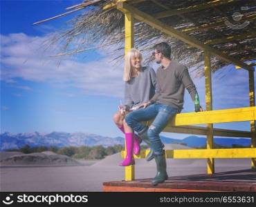 young couple drinking beer together at the beach. Couple Drinking Beer Together in empty beach bar during autumn time colored filter