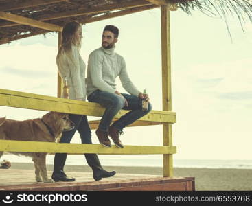 young couple drinking beer together at the beach. Couple Drinking Beer Together in empty beach bar during autumn time colored filter