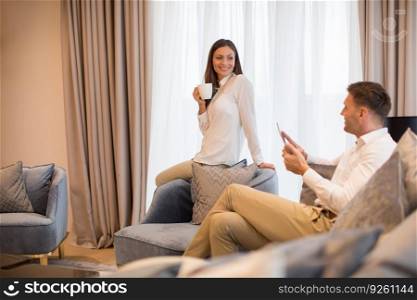 Young couple drinking coffee and using digital tablet in the luxury contemporary apartment