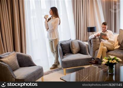 Young couple drinking coffee and using digital tablet in the luxury contemporary apartment