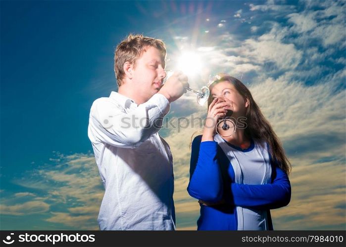 Young couple drinking red wine shot against the sky
