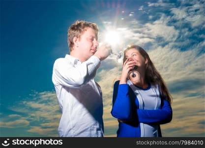 Young couple drinking red wine shot against the sky