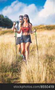 Young couple during a Nordic walking hike on hillside trail