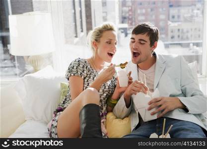 Young couple eating food with chopsticks