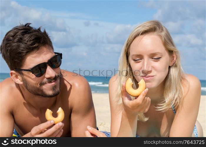 young couple eating on the beach