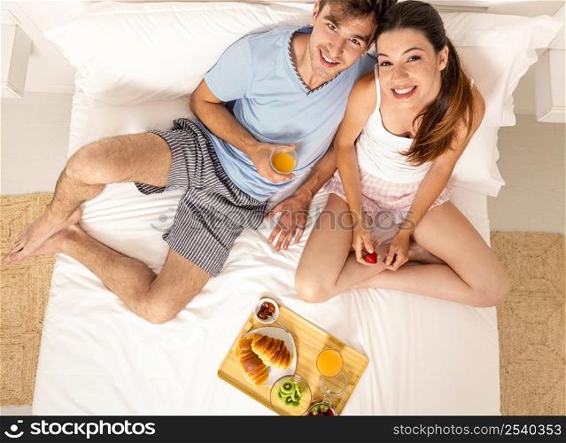 Young couple eating the breakfast on the bed