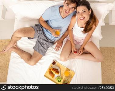 Young couple eating the breakfast on the bed