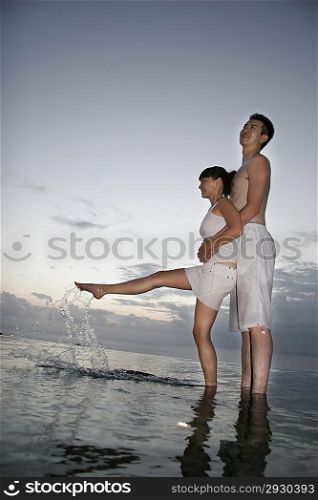 Young couple embrace at the edge of water