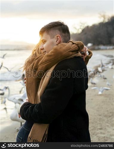 young couple embracing beach winter