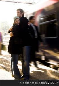 Young couple embracing each other at a railroad station platform