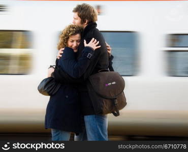 Young couple embracing each other at a railroad station platform